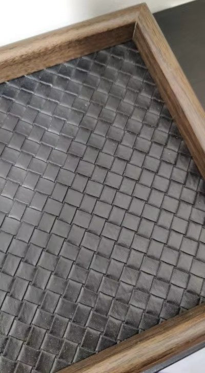 Musta koristetarjotin, jossa punottu pohja ja puunvärinen kehys