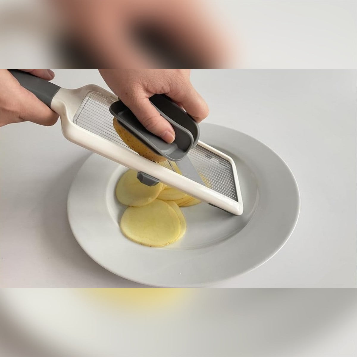 Perunaa viipaloidaan ruokapidikkeen avulla lautasen päällä