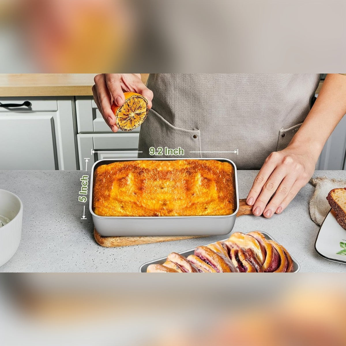 Kaksi leipävuokaa, joissa kakku ja pullapitko keittiön tasolla, mitat 9,2 ja 5 tuumaa reunojen yli