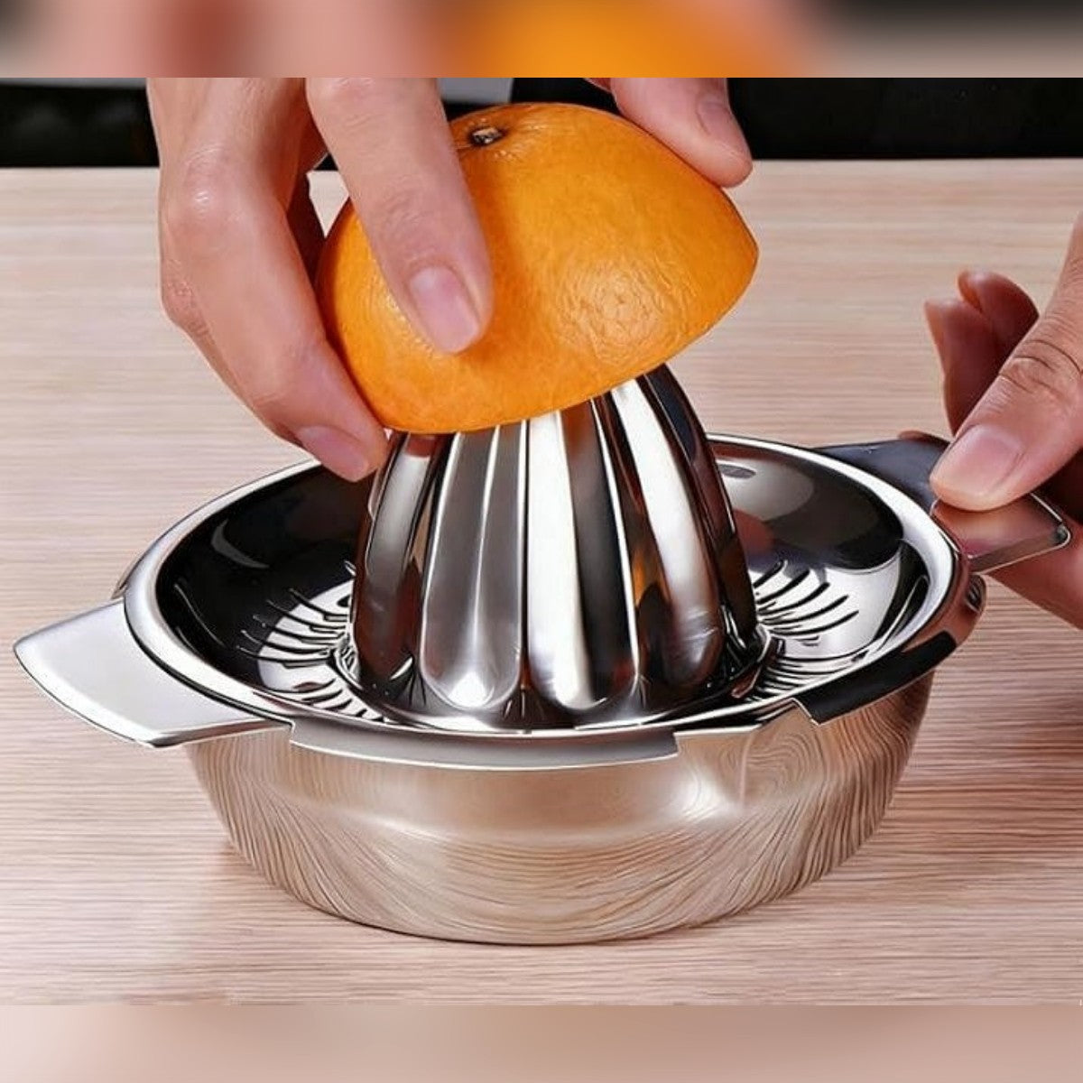 Appelsiinin puolikas puristetaan kartiolla, toinen käsi pitää sitruspuristimesta kiinni