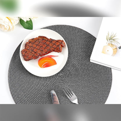 Pyöreä tummanharmaa pöytätabletti, jolla on lautanen, veitsi ja haarukka valkoisella pöydällä