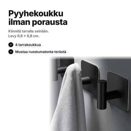 Pyyhekoukku ilman porausta: mustat tarrakoukut harmaalla seinällä, yhdessä koukussa pyyhe – levy 6,8 × 6,8 cm