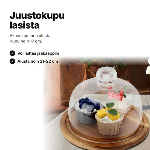 Juustokupu lasista akaasiapuisella alustalla, kuvun alla pieniä leivonnaisia – kupu noin 17 cm