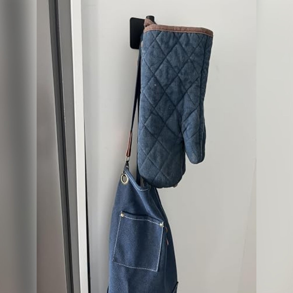 Ostajan kuva: musta koukku oven vieressä, koukussa patalappu ja esiliina