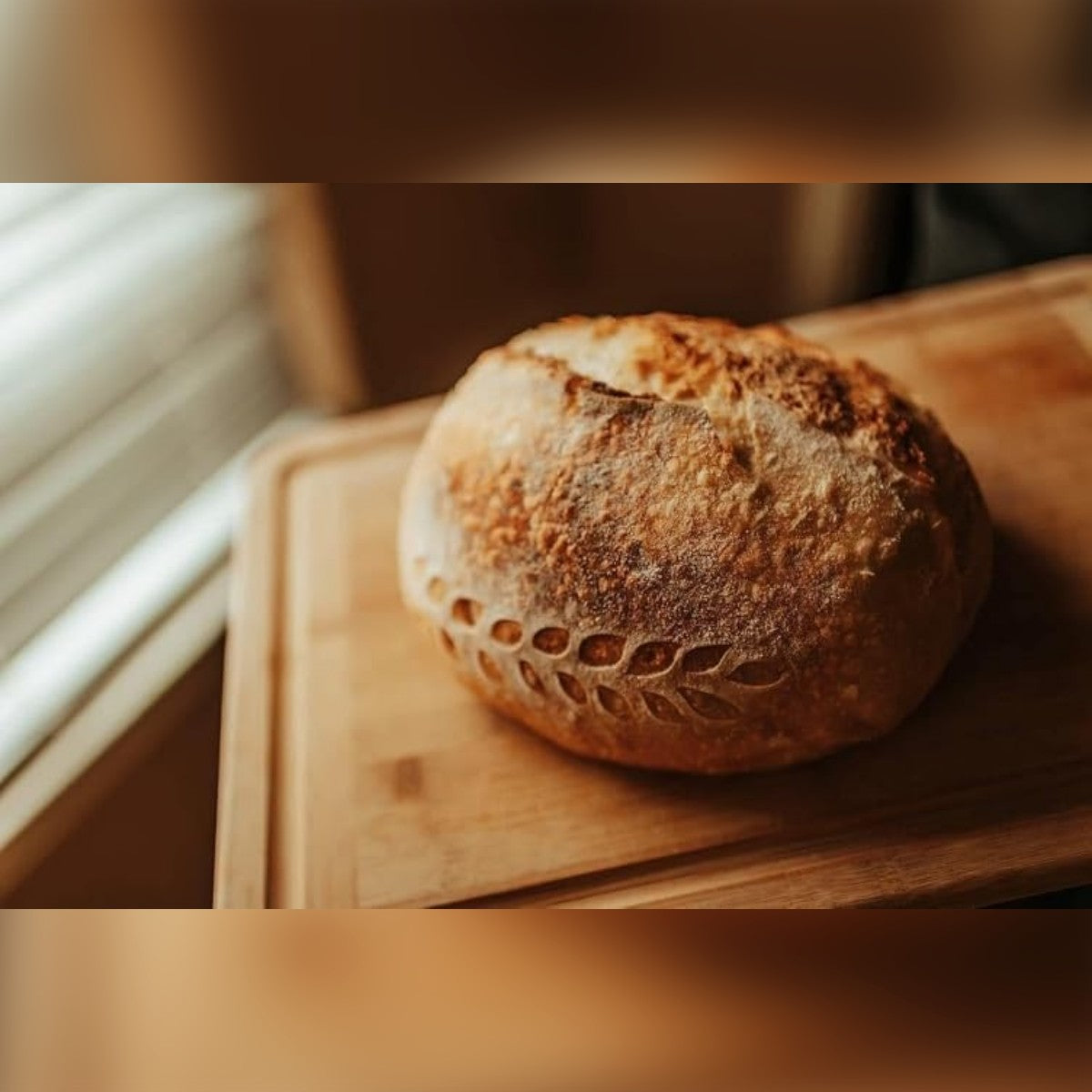 Ostajan kuva: pyöreä juurileipä, kohotettu korissa, leikkuulaudalla