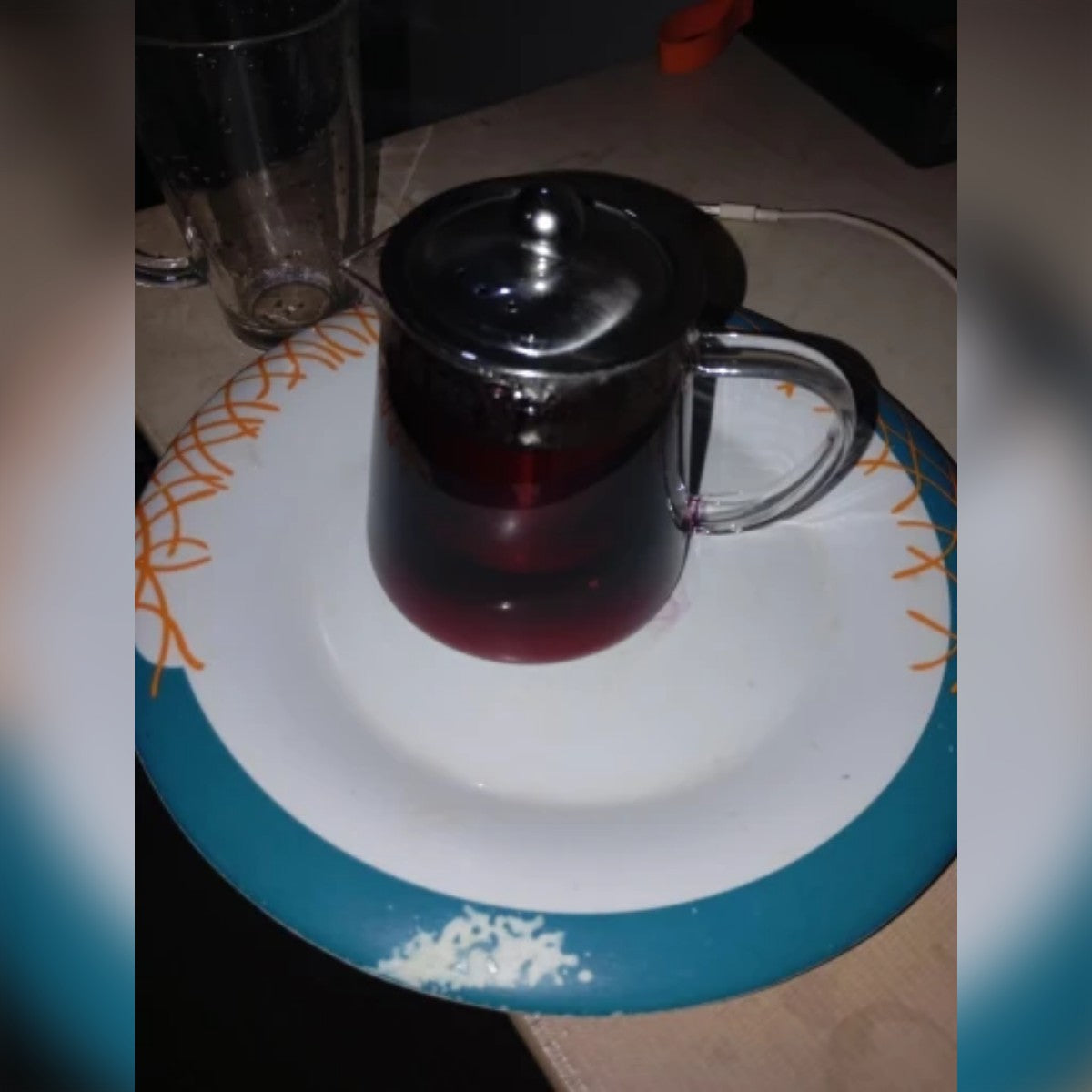 Ostajan kuva: lasinen teekannu täynnä hibiskusteetä lautasella